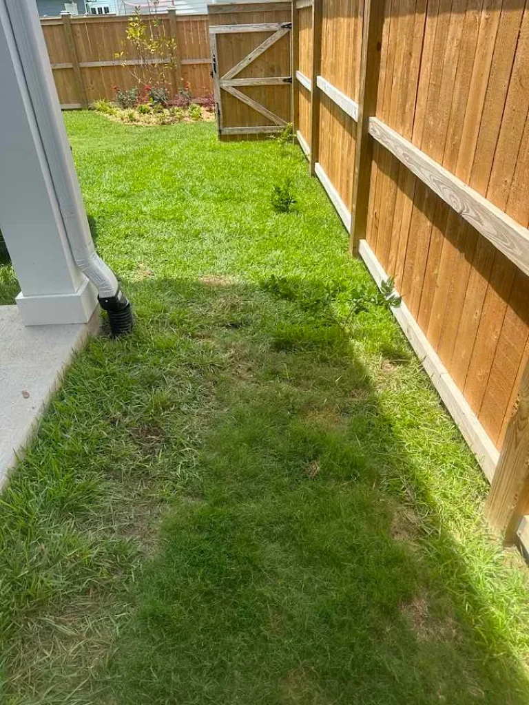 Downspout to underground drain diverting water outside of low lying are for proper yard drainage.